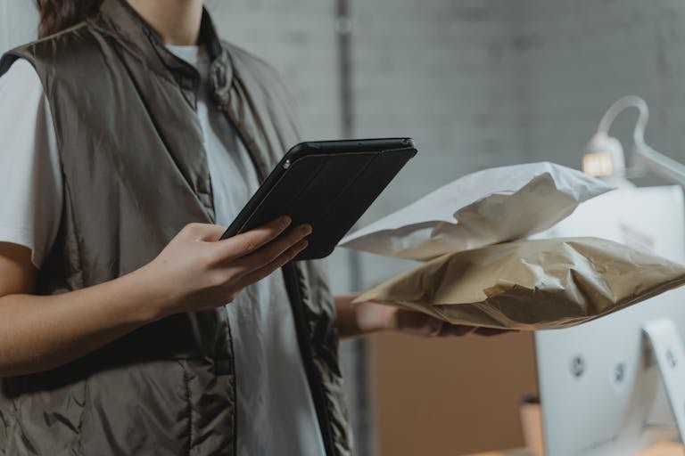 A business person using a tablet to manage packages in an indoor setting, highlighting technology and logistics.